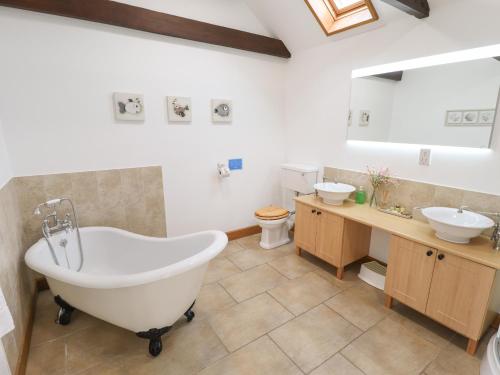 a bathroom with a tub and two sinks and a toilet at Barn Cottage in Alford
