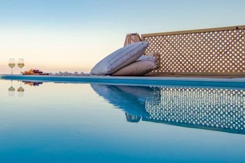 a swimming pool with a bench and a glass of wine at Georgianna's suite with private pool , 'greysuite' in Kómpoi