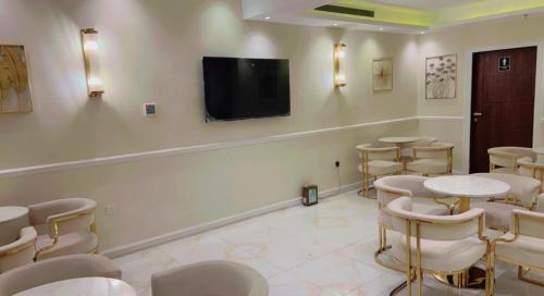 a room with tables and chairs and a flat screen tv at Ghima Jeddah in Jeddah