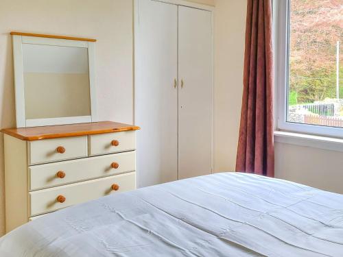 a bedroom with a dresser and a bed with a mirror at Craik Forestry Cottage in Teviothead