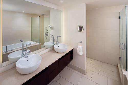 a bathroom with two sinks and two mirrors at Allegria Hotel in Long Beach