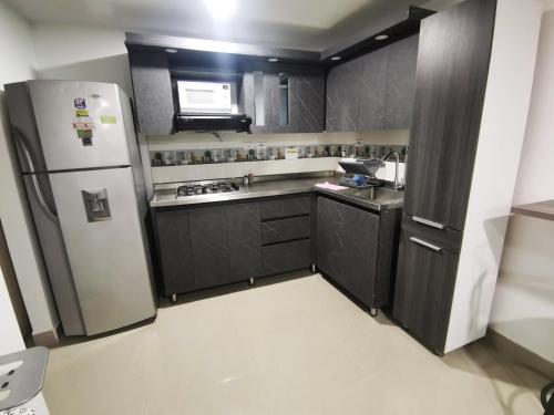 a kitchen with black cabinets and a refrigerator at Andaliving Campo Valdes Hospedaje in Medellín