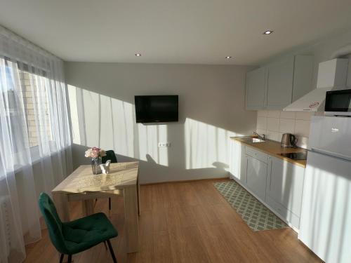 a small kitchen with a table and a green chair at Stay in center #Šiauliai in Šiauliai