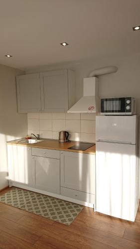 una cocina con armarios blancos y electrodomésticos blancos en Stay in center #Šiauliai en Šiauliai