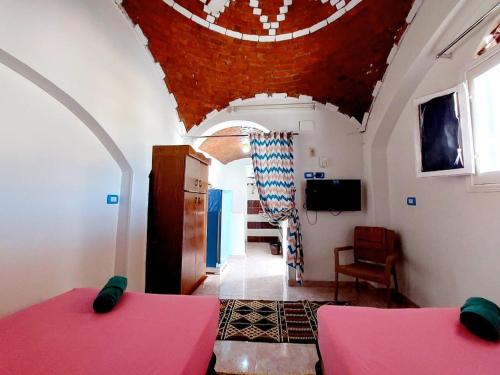 a bedroom with two beds and a red ceiling at Gamal Robob Nubian Guest House in Aswan