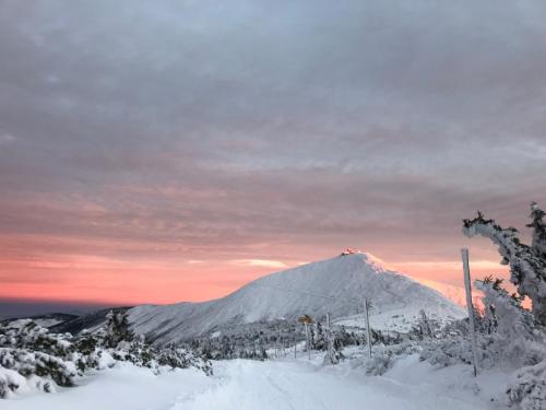 a snow covered mountain with a sunset in the background at Willa Tyrolczyk in Karpacz
