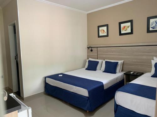 a hotel room with two beds with blue pillows at Summit Beach Hotel Boiçucanga in Boicucanga