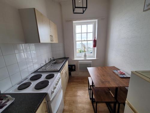 a kitchen with a stove and a table and a window at Sea View flat 2 with Fast WiFi and FREE parking in Scarborough