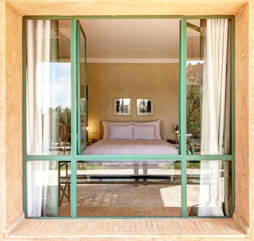 a bedroom with a bed through a glass window at Jenan Mayshad Marrakech, Boutique hotel with Pool & Private Padel Court in Marrakech