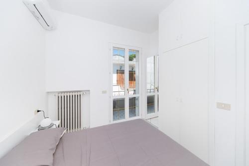 biały pokój z łóżkiem i oknem w obiekcie Villetta Belgrado w Cesenatico