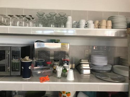 a kitchen counter with plates and dishes on a shelf at Hotel Sociedad y Maristas in Tecolutla