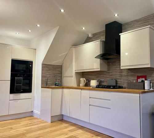 una cocina con armarios blancos y electrodomésticos negros en HU1 Hull City Centre Modern Apartment WIFI BATH H9, en Hull