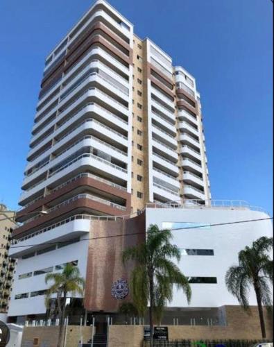 un grand bâtiment avec des palmiers devant lui dans l'établissement Apartamento novo Vila Guilhermina, à Praia Grande