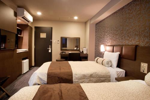 a hotel room with two beds and a bathroom at Kuretake Inn Premium Shizuoka Ekimae in Shizuoka