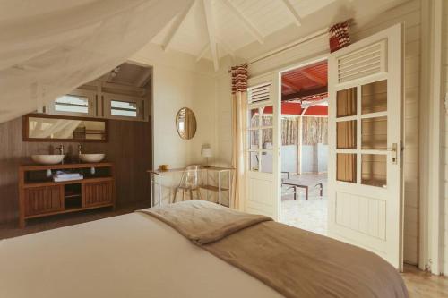 - une chambre avec un lit, une table et une porte dans l'établissement Elégance et Charme Créole, Villa Sahana vue Mer avec Jacuzzi, à Bouillante