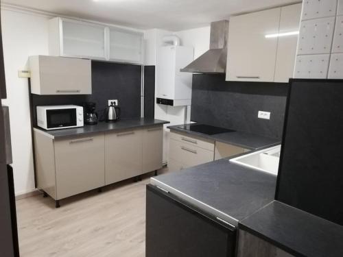 une cuisine avec des placards blancs et un comptoir noir dans l'établissement L'appart des Sotrés, à Saint-Dié-des-Vosges
