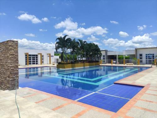 a large blue swimming pool with palm trees and a building at Condominio Villa Esperanza in Flandes