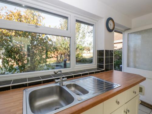 a kitchen with a sink and two windows at 16 Dean Court in Lydney