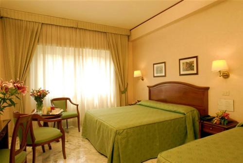 ein Hotelzimmer mit einem Bett, einem Tisch und einem Fenster in der Unterkunft Hotel San Pietro in Rom