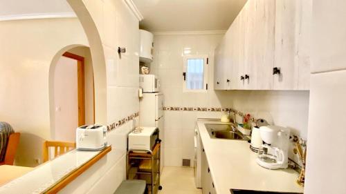cocina con armarios blancos y encimera en Apartamento Mimosa en Torrevieja