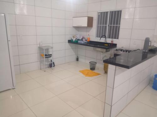 cocina de azulejos blancos con encimera y fregadero en Casa em Paripueira, en Paripueira