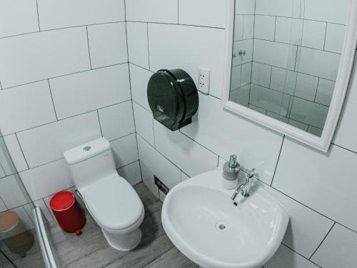 Baño blanco con aseo y lavamanos en Alpes Lima Kennedy Hostel, en Lima