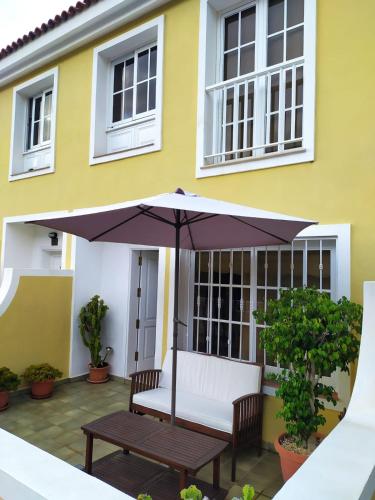 an umbrella on a patio in front of a yellow house at Casa Sagittarius Ocean view in San Marcos
