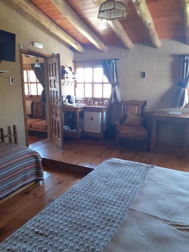 a room with a bed and a desk and windows at Posada Almazen in Las Compuertas