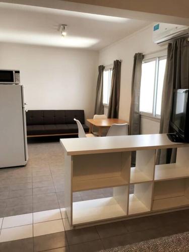 ein Wohnzimmer mit einem Tisch und eine Küche mit einem TV in der Unterkunft Monoambiente céntrico in Tandil