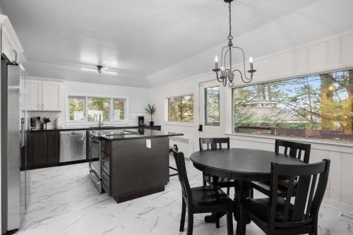 a kitchen with a black table and chairs and a table and a kitchen with at Lakefront House by Michigan Waterfront Luxury Properties in Norton Shores
