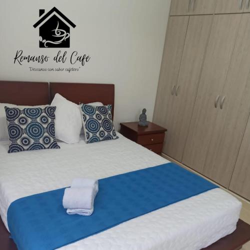a bedroom with a bed with blue and white pillows at Remanso del café in La Tebaida