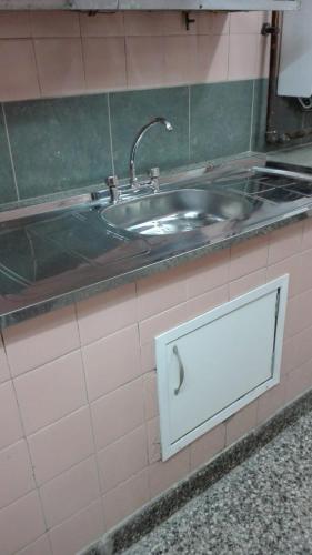 un lavabo en una pared de azulejos con una puerta de metal en Alojamiento Avellaneda en Rosario