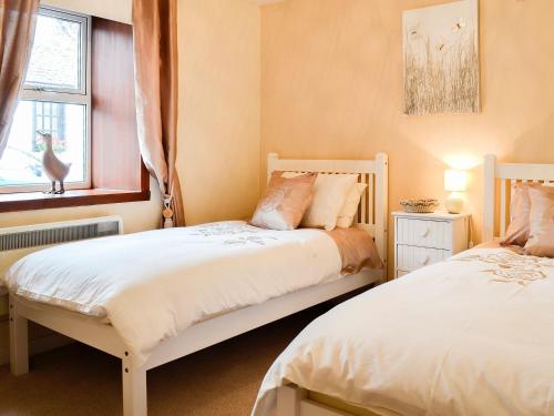 a bedroom with two beds and a window at Creel Cottage in Auchmithie