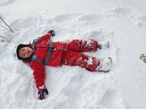 a young child is laying in the snow at SNOWED INN apartment in Dinner Plain