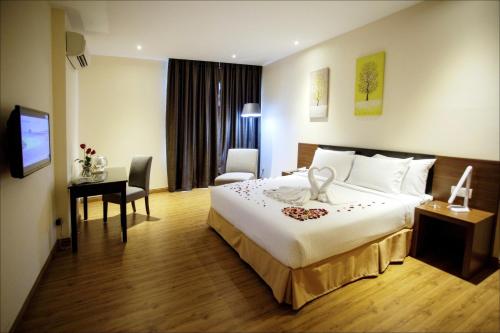 a hotel room with a bed and a desk and a television at Cathayana Hotel Kuantan in Kuantan