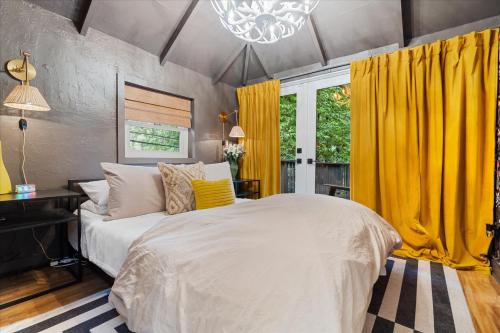 1 dormitorio con cama blanca y cortinas amarillas en The Black Nest - Hot Tub Romantic Getaway, en Guerneville