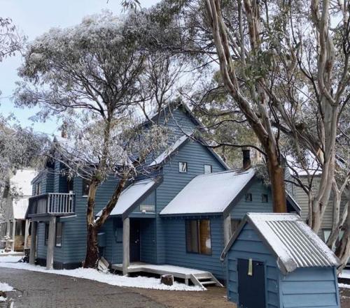 a blue house with snow on top of it at SNOWED INN apartment in Dinner Plain