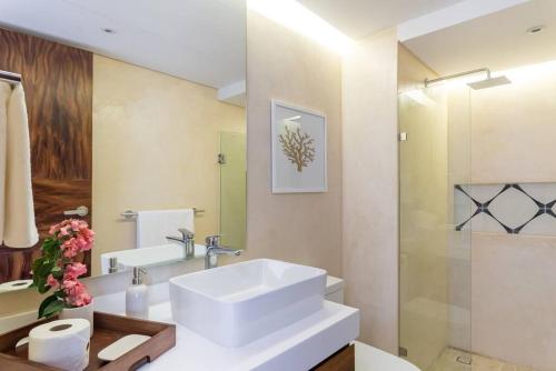 een badkamer met een witte wastafel en een spiegel bij Cozy Apartments at Central Park Lagunas in Tulum
