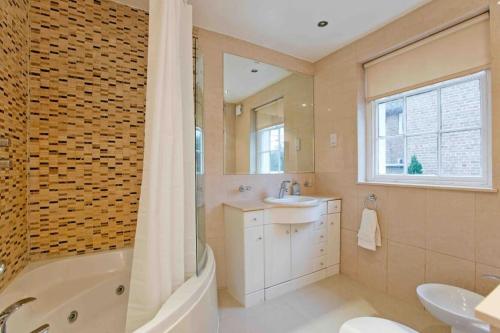 a bathroom with a tub and a sink and a bath tub at Beautiful 4 Bed House by Regents Park in London