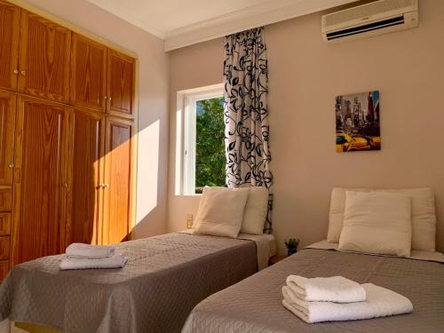 1 dormitorio con 2 camas y ventana en VillAri Lefkas Suites en Exanthia