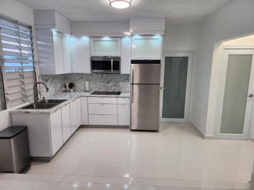 a kitchen with white cabinets and a stainless steel refrigerator at San Juan Home in San Juan