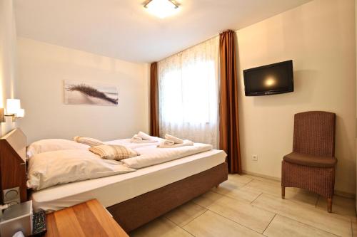 1 dormitorio con cama, ventana y silla en Villa Verdi - Ferienwohnung 4, en Wangerooge