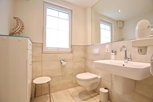 a white bathroom with a sink and a toilet at Villa Verdi - Ferienwohnung 4 in Wangerooge