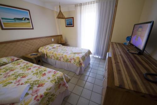 a hotel room with two beds and a flat screen tv at Pousada Manga Rosa Beira Mar in Natal