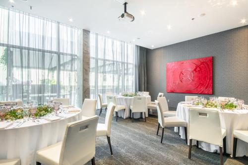 a restaurant with white tables and white chairs and a red painting at HOTEL10 in Montréal