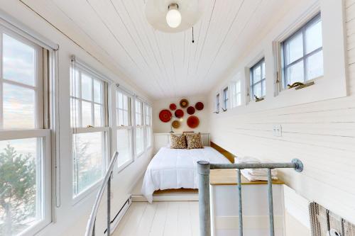 1 dormitorio con paredes y ventanas blancas y 1 cama en The Lighthouse, en Provincetown