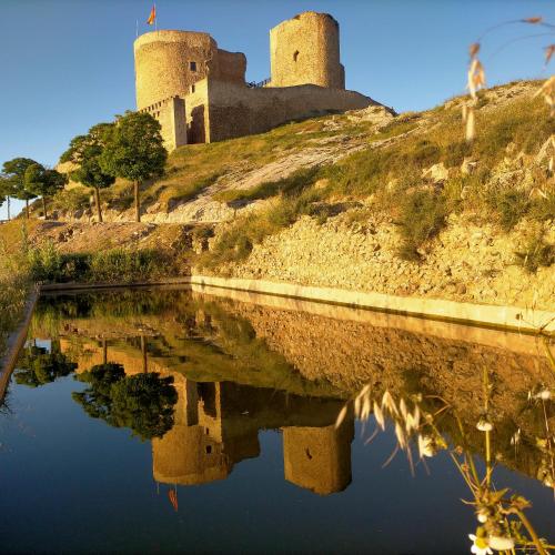 a castle on a hill with a reflection in the water at Azafrán Consuegra in Consuegra