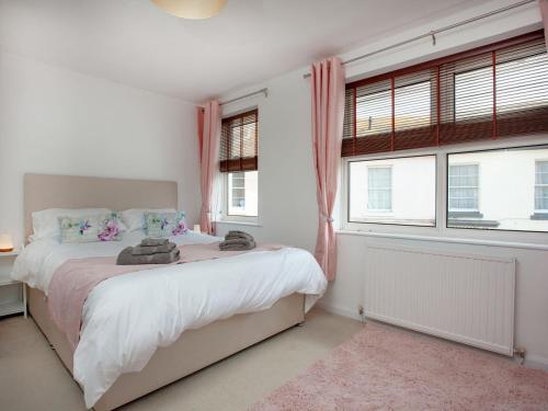 a bedroom with a bed and two windows at Jubilee Cottage in Dawlish