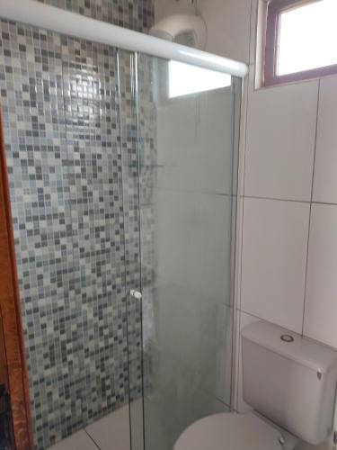 a bathroom with a toilet and a glass shower at Hotel Rainha in Itapoa