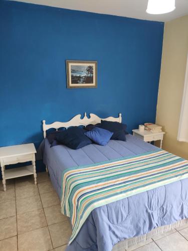 a blue bedroom with a bed with a blue wall at Hotel Rainha in Itapoa